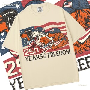 May include: A cream-coloured t-shirt with a graphic of three dogs wearing caps and bandanas, set against an American flag design. The text "250 YEARS OF FREEDOM" is printed below. The shirt has a crew neck and short sleeves.