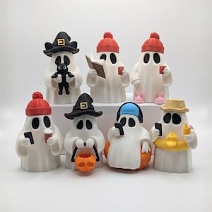 Op de afbeelding: Een verzameling witte spookfiguren, elk met unieke accessoires. Sommige geesten dragen hoeden, mutsen of koptelefoons. Eén houdt een zwarte kat vast, een ander een boek, en anderen houden telefoons of bekers vast.