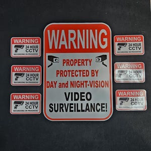 May include: A set of red and white warning signs. The main sign states "WARNING PROPERTY PROTECTED BY DAY and NIGHT-VISION VIDEO SURVEILLANCE!". Smaller signs read "WARNING 24 HOUR CCTV RECORDING IN PROGRESS".