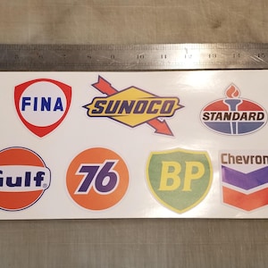 Può includere: Un foglio di adesivi con loghi di stazioni di servizio d'epoca. I loghi sono di vari colori e includono Exxon, Fina, Sunoco, Standard, Petro-Canada, Esso, Gulf, 76, BP, Chevron e Amoco.