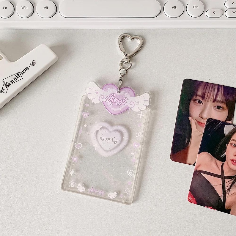 Pu&ograve; includere: Un portachiavi in plastica trasparente con un cuore e ali viola. Il cuore ha la scritta "Angel" su di esso. Il portachiavi ha una catena argentata e un anello a forma di cuore.