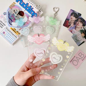 Pu&ograve; includere: Cinque portachiavi in plastica trasparente con un design a forma di cuore. Ogni portachiavi &egrave; di un colore diverso: rosa, azzurro, giallo, verde e viola. I portachiavi hanno una finitura scintillante e presentano un piccolo cuore con la parola "cute" scritta su di esso. I portachiavi sono appesi a una catena argentata con un ciondolo a forma di cuore.