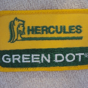 May include: A yellow and green embroidered patch with the text "Hercules Green Dot" and a green stylised image of a horse's head.