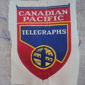 May include: A vintage Canadian Pacific Telegraphs patch. The patch features a shield design with red, blue, and yellow accents. The text "CANADIAN PACIFIC TELEGRAPHS" is prominently displayed.