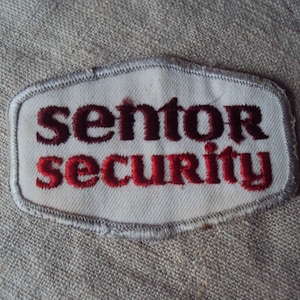 May include: White embroidered patch with red and black lettering that reads "senior security".