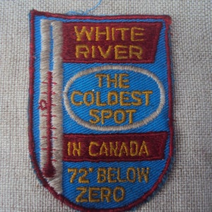 May include: A blue and red embroidered patch with the text "White River The Coldest Spot In Canada 72' Below Zero".