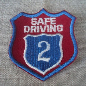 May include: Red and blue embroidered patch with the text "SAFE DRIVING 2" in white.