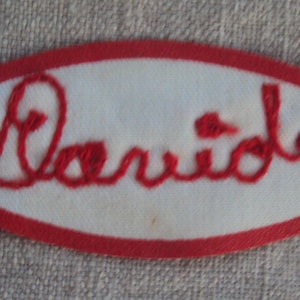 Pode incluir: Etiqueta ovalada bordada em vermelho com a palavra "Serviço" em fio branco.