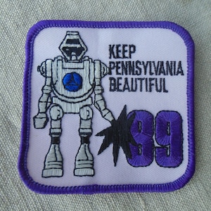 May include: Embroidered patch with a robot design, a blue circle, and the text "KEEP PENNSYLVANIA BEAUTIFUL 99". The patch has a white background with a purple border.