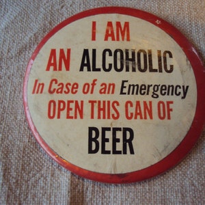 May include: A red and white button with the text "I am an alcoholic. In case of an emergency open this can of beer."