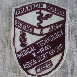 Könnte beinhalten: Ein gestickter Aufnäher in Rotbraun und Weiß mit dem Text "Franklin School Science & Arts Medical Technology X-Ray Medical Secretaryship".