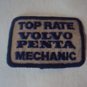 May include: A blue and white embroidered patch that reads "Top Rate Volvo Penta Mechanic".