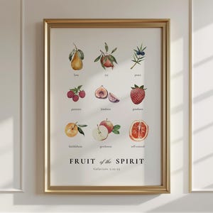 May include: A framed print with a white background and gold frame. The print features a watercolour illustration of different fruits with the text "FRUIT of the SPIRIT Galatians 5:22-23" at the bottom.