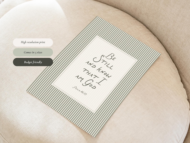 May include: A rectangular print with a striped background in shades of green and white. The print features the text "Be Still and Know That I Am God" in elegant script. The print is displayed on a neutral-toned surface.