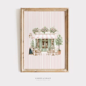 Può includere: Stampa artistica di un caffè con una tenda a strisce rosa e bianche, una porta verde e tavolini con sedie. L'opera d'arte è incorniciata in una cornice di legno color oro e su uno sfondo a righe rosa e bianche.
