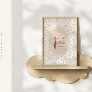 May include: A framed wall art print featuring a stack of books tied with a pink ribbon, set within an oval frame. The background is a floral pattern. The print is displayed on a cloud-shaped wooden shelf. The text "GARDEN of GRACE TIMELESS WALL ART" is visible.