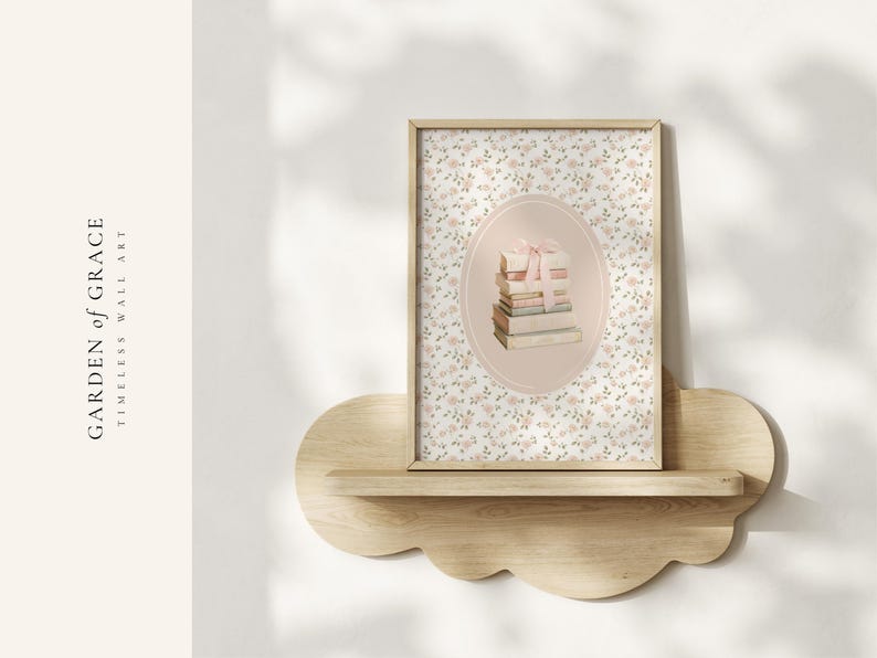 May include: A framed wall art print featuring a stack of books tied with a pink ribbon, set within an oval frame. The background is a floral pattern. The print is displayed on a cloud-shaped wooden shelf. The text "GARDEN of GRACE TIMELESS WALL ART" is visible.