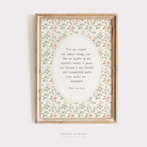 Op de afbeelding: Een ingelijste print met een bloemenpatroon en een ovale tekstballon. De tekst citeert Psalm 139:13-14. De lijst is lichtbruin. Geschikt voor interieurdecoratie.