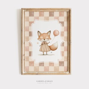 May include: A watercolour illustration of a fox wearing a dress and holding a pink balloon. The fox is surrounded by stars and the background is a chequered pattern in shades of brown and pink. The image is framed in a light brown frame with the text "GARDEN of GRACE TIMELESS WALL ART" at the bottom.