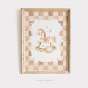 Può includere: Una stampa incorniciata con uno sfondo a scacchi in tonalità di marrone e rosa. La stampa presenta un'illustrazione ad acquerello di un cavallo a dondolo bianco con una sella marrone e una palla a forma di stella. Il testo "GARDEN of GRACE TIMELESS WALL ART" è in fondo alla stampa.
