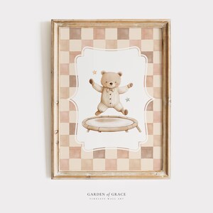 Può includere: Un'illustrazione incorniciata di un orso marrone che indossa un abito bianco e marrone che salta su un trampolino. Lo sfondo è un motivo a scacchi in tonalità di marrone e rosa. Il testo "GARDEN of GRACE TIMELESS WALL ART" è nella parte inferiore dell'immagine.
