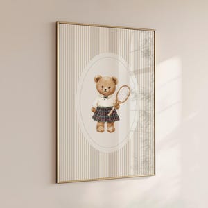 K&ouml;nnte beinhalten: Gerahmter Druck mit einer Aquarellillustration eines Teddyb&auml;ren, der einen Tennisschl&auml;ger h&auml;lt. Der B&auml;r tr&auml;gt ein wei&szlig;es Hemd, einen karierten Rock und eine schwarze Fliege. Der Hintergrund hat vertikale Streifen.