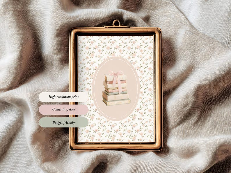 May include: A framed print with a gold-colored frame. The print features a floral pattern background and a central oval with a stack of books tied with a pink ribbon. Text on the image reads: High resolution print, Comes in 5 sizes, Budget friendly.
