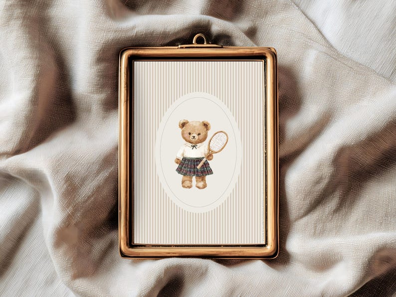 K&ouml;nnte beinhalten: Gerahmter Druck mit einer Aquarellillustration eines Teddyb&auml;ren in Tennisbekleidung, der einen Schl&auml;ger h&auml;lt. Der B&auml;r befindet sich vor einem gestreiften Hintergrund in einem ovalen Rahmen. Der Rahmen ist goldfarben.