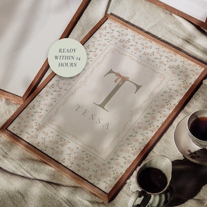 Pu&ograve; includere: Stampa floreale incorniciata con il nome "Tessa" e una grande lettera "T" con un fiocco. La stampa &egrave; in una cornice di legno, con una tazza di t&egrave; e panna accanto. Il testo "READY WITHIN 24 HOURS" &egrave; in un cerchio.