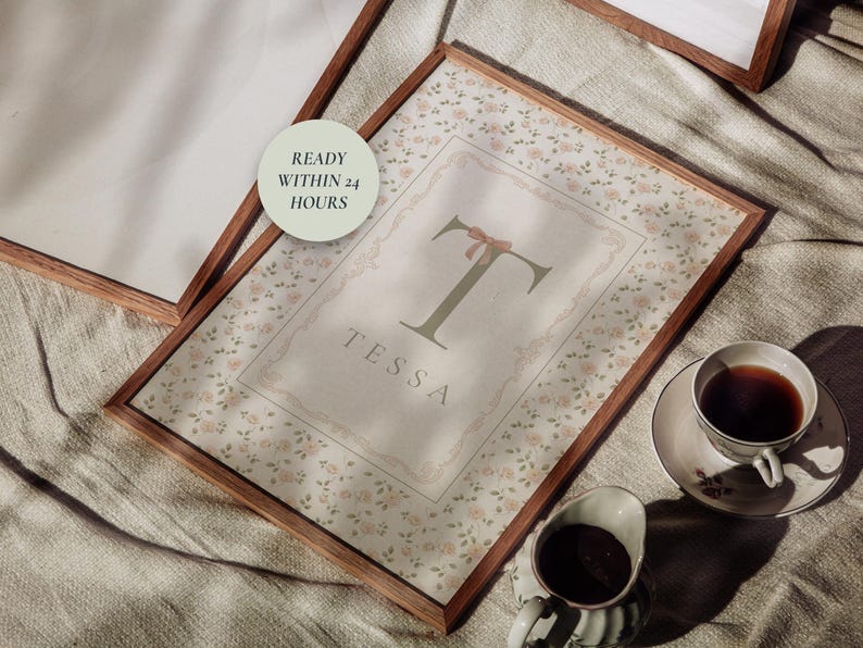 Pu&ograve; includere: Stampa floreale incorniciata con il nome "Tessa" e una grande lettera "T" con un fiocco. La stampa &egrave; in una cornice di legno, con una tazza di t&egrave; e panna accanto. Il testo "READY WITHIN 24 HOURS" &egrave; in un cerchio.
