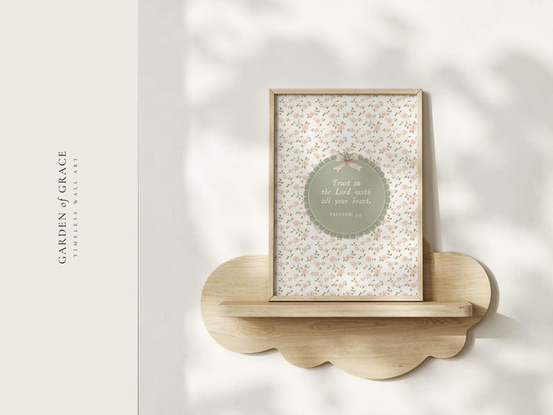 Op de afbeelding: Een ingelijste bloemenprint met de tekst "Trust in the Lord with all your heart" staat op een houten, wolkvormig plankje. De print heeft een lichtbeige achtergrond met kleine roze en witte bloemen.