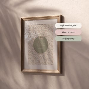 Op de afbeelding: Een ingelijste print met een goudkleurige lijst hangt aan een beige muur. De print heeft een bloemenpatroon en een cirkelvormig ontwerp met de tekst 'Vertrouw op de Heer met heel je hart'. Extra tekst op de afbeelding zegt 'Hoge resolutie print', 'Verkrijgbaar in 5 maten' en 'Budgetvriendelijk'.