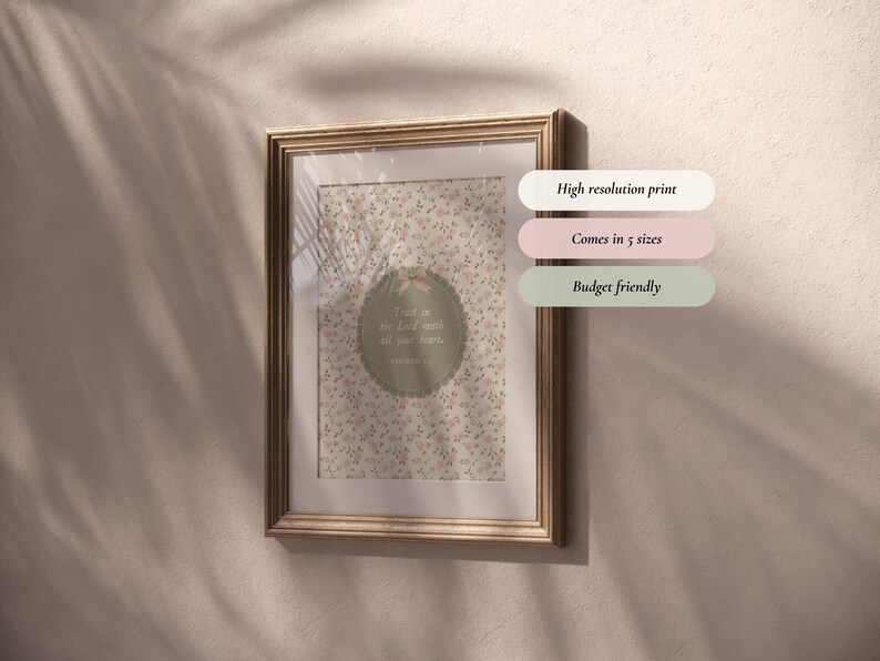Op de afbeelding: Een ingelijste print met een goudkleurige lijst hangt aan een beige muur. De print heeft een bloemenpatroon en een cirkelvormig ontwerp met de tekst 'Vertrouw op de Heer met heel je hart'. Extra tekst op de afbeelding zegt 'Hoge resolutie print', 'Verkrijgbaar in 5 maten' en 'Budgetvriendelijk'.