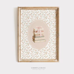 May include: A framed wall art print featuring a stack of books tied with a pink ribbon, set against a floral background. The artwork is enclosed in a distressed, light brown wooden frame, with the text "GARDEN OF GRACE" at the bottom.