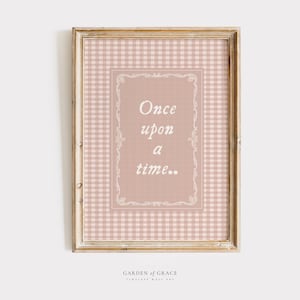 May include: Framed wall art with a light brown wooden frame. The artwork features a pink and white gingham pattern background with a rectangular center in a darker pink shade. The text "Once upon a time.." is displayed in white script.