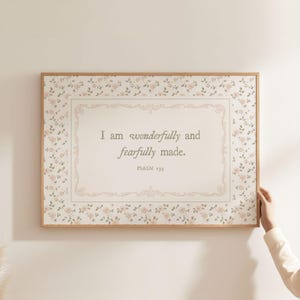 May include: A framed print featuring the text "I am wonderfully and fearfully made. Psalm 139." The print has a floral border with small pink roses on a light beige background.
