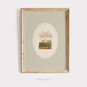 May include: A framed print featuring a stack of vintage suitcases tied with a pink bow, set against a dotted background. The artwork is in an oval shape, with the words "GARDEN OF GRACE" and "TIMELESS WALL ART" at the bottom.