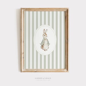 Puede incluir: Una impresión enmarcada con un fondo a rayas verde y blanco. Un óvalo blanco contiene una ilustración de acuarela de un conejo marrón con una chaqueta verde. El texto "GARDEN of GRACE" está impreso debajo de la imagen.