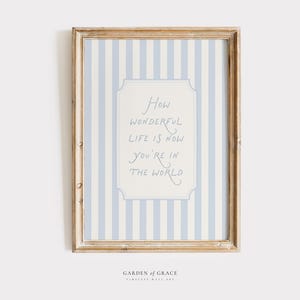 Könnte beinhalten: Gerahmtes Wandbild mit hellblau-weiß gestreiftem Hintergrund. Das Kunstwerk zeigt ein cremefarbenes Rechteck mit dem handgeschriebenen Text: "How wonderful life is now you're in the world."