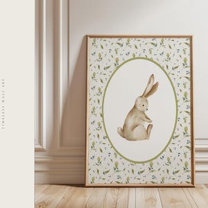 Puede incluir: Una impresi&oacute;n enmarcada con una ilustraci&oacute;n de acuarela de un conejo sentado. El conejo est&aacute; dentro de un &oacute;valo verde sobre un fondo de patrones florales. El marco es de madera, y el texto "GARDEN OF GRACE TIMELESS WALL ART" est&aacute; a la izquierda.
