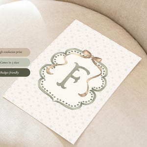 May include: A watercolor print featuring the letter "F" in a decorative frame with a bow. The print has a light background with small star patterns. Text on the left side reads "High resolution print", "Comes in 5 sizes", and "Budget friendly".