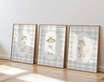 May include: Three framed prints with a gray and white checkered background. Each print features a white goose wearing a straw hat and a pink bow. The goose in the left print is facing left, the goose in the center print is facing right, and the goose in the right print is facing left.