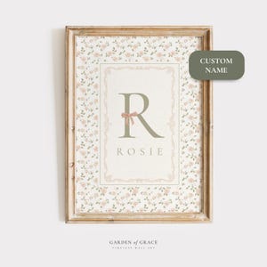 Pu&ograve; includere: Stampa artistica da parete incorniciata con sfondo a motivi floreali e un design centrale con la lettera "R" e il nome "Rosie". La stampa include un bordo decorativo e un fiocco. Il testo "CUSTOM NAME" &egrave; su un'etichetta verde.