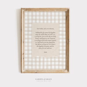 May include: A framed print with a beige and white gingham pattern background. The print features the Lord's Prayer in a white font on a beige background. The frame is a light wood colour. The text at the bottom of the print reads "GARDEN of GRACE TIMELESS WALL ART".