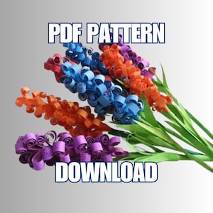 May include: A colorful paper flower arrangement with stems and leaves. The flowers are made of rolled paper in shades of orange, blue, and purple. The text "PDF PATTERN DOWNLOAD" is displayed in a blue font.