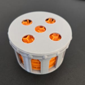 May include: A gray and orange plastic puzzle toy with six holes on the top and a cylindrical base. The holes are filled with orange interlocking pieces.
