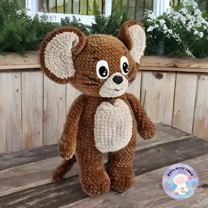 Könnte beinhalten: Ein braunes, gehäkeltes Plüschtier in Form einer Maus mit großen Ohren und großen Augen. Die Maus hat einen beigefarbenen Bauch und eine schwarze Nase.