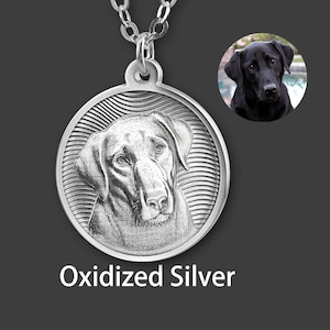 May include: Silver pendant necklace with a detailed dog portrait. The round pendant has a textured border and hangs from a silver chain. The text "Oxidized Silver" is below the pendant. A smaller image of a black dog is in the upper right corner.