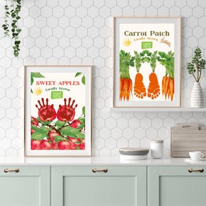 May include: Two printable art prints for a nursery or child's room. The prints feature handprint and footprint outlines with a fruit and vegetable theme. The first print features red apples and the text "Sweet Apples Locally Grown Farm Fresh". The second print features orange carrots and the text "Carrot Patch Locally Grown Farm Fresh".
