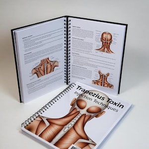 May include: A spiral-bound instructional manual titled Trapezius Toxin Injection Techniques. The cover features a detailed anatomical illustration of the human neck and shoulder muscles. The open pages display diagrams and text regarding muscle anatomy.